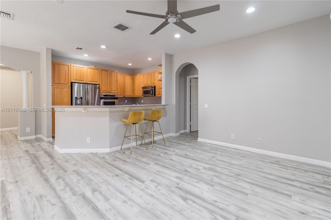 Kitchen featuring wood-finish cabinetry, breakfast bar, stainless steel appliances, recessed lighting, and wood-finish flooring