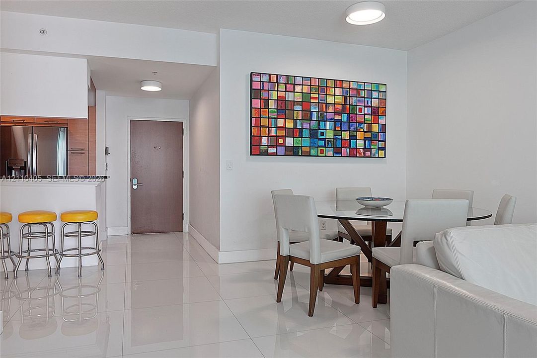 Open-concept space featuring polished tile flooring, recessed ceiling lighting, and a kitchen peninsula with a dark stone countertop