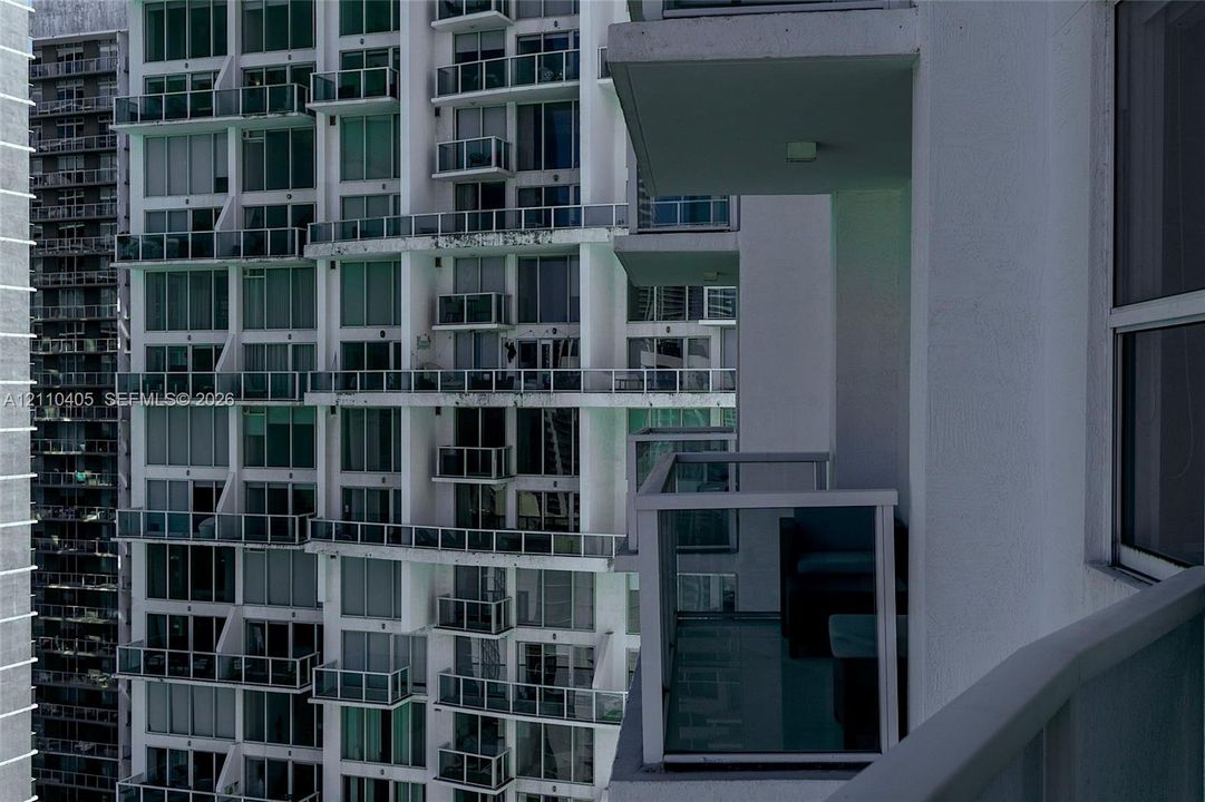 High-rise exterior featuring individual balconies with glass railings and floor-to-ceiling windows