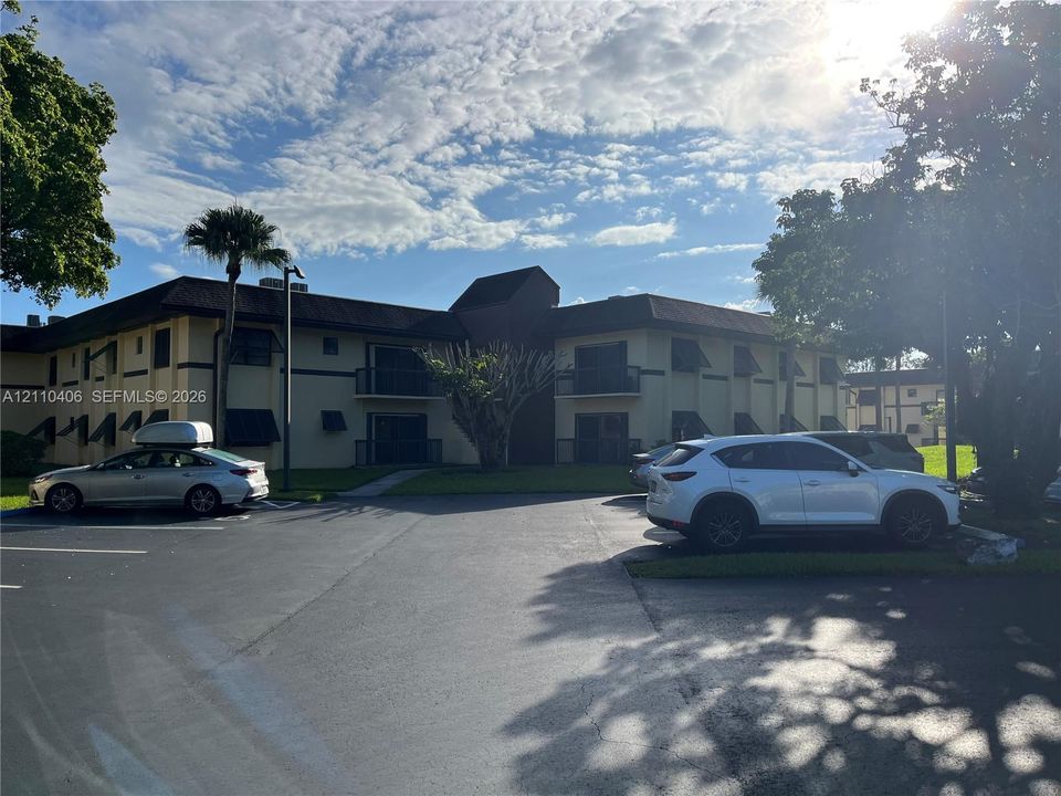 Multi-story building exterior featuring smooth stucco siding, low-pitch roofline, and private balconies with railings