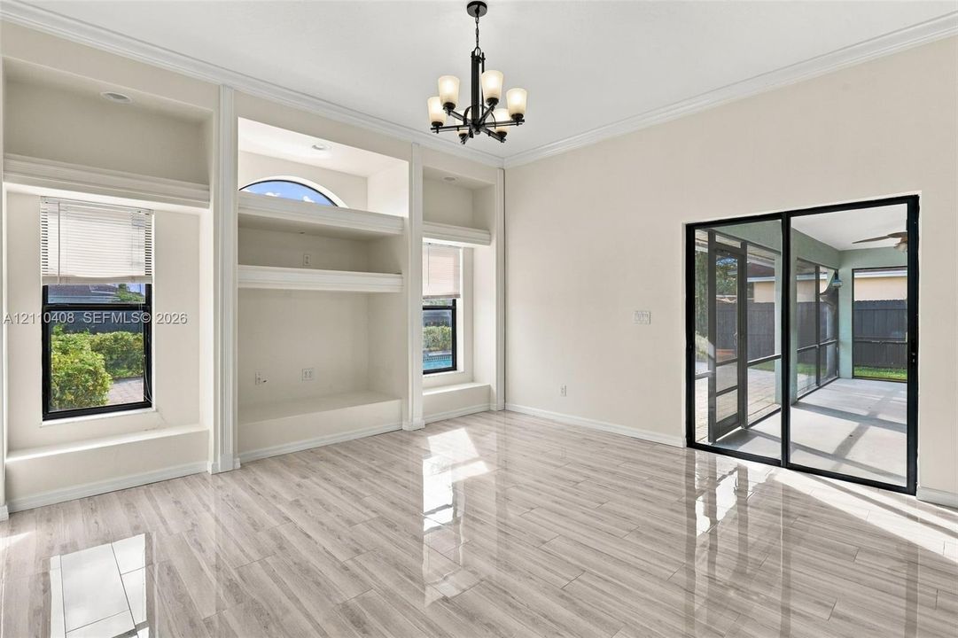 Interior space featuring wood-finish flooring, built-in recessed cabinetry, a five-light chandelier, and floor-to-ceiling sliding glass doors