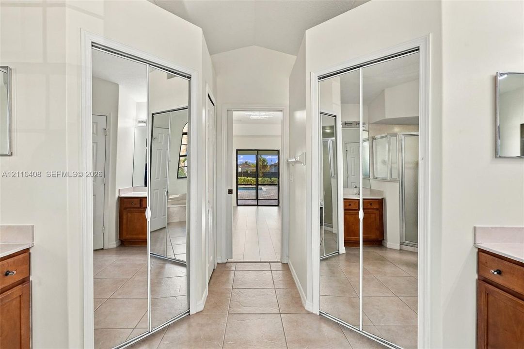 Dual mirrored sliding-door closets, tile flooring, and symmetrical cabinetry with light-toned countertops