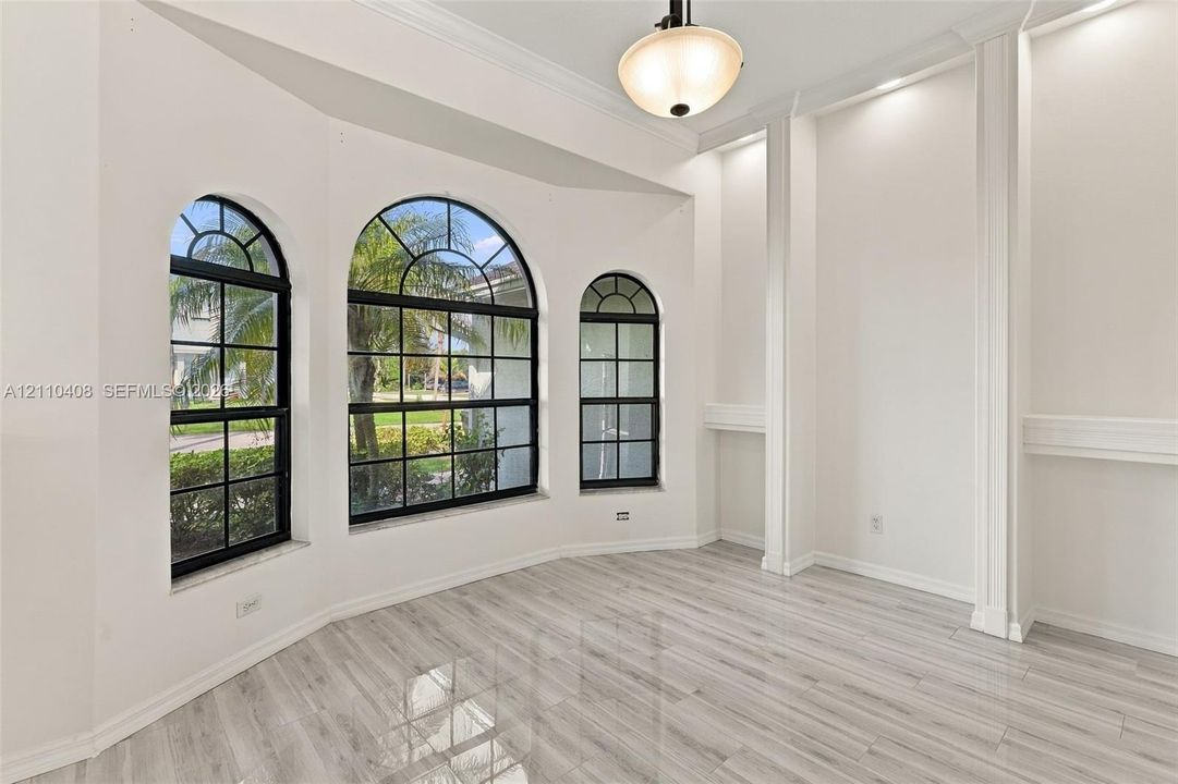 Arched windows with grid detailing, wood-finish tile flooring, built-in recessed shelving, and a decorative ceiling-mounted pendant light fixture