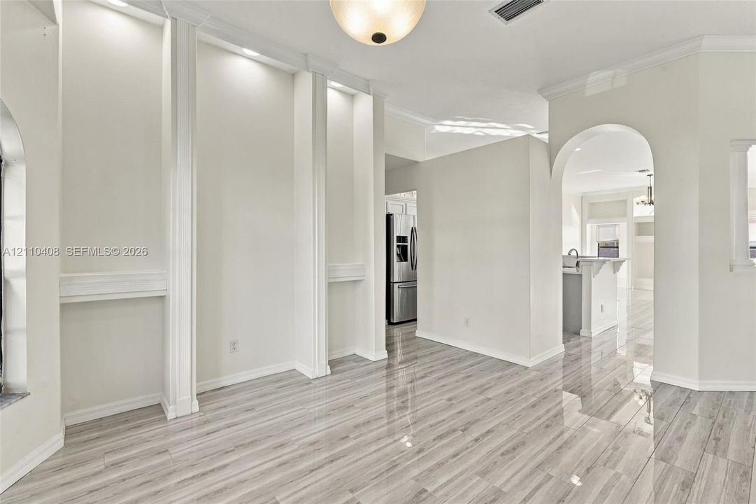 Neutral interior space featuring polished tile flooring, recessed wall niches with integrated lighting, and an arched architectural opening