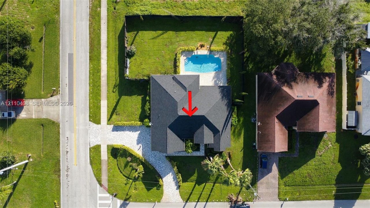 Aerial perspective featuring a residential property with a shingle roof, a fenced backyard, and a rectangular in-ground swimming pool
