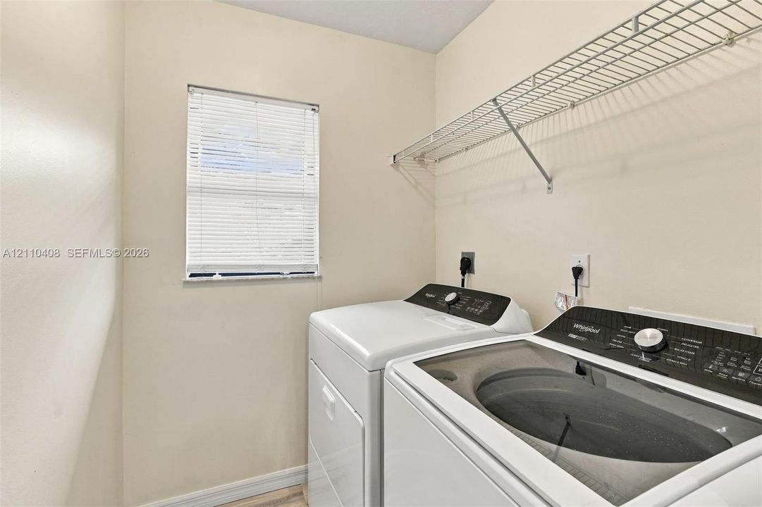 Laundry room featuring a window with horizontal blinds and integrated wire shelving