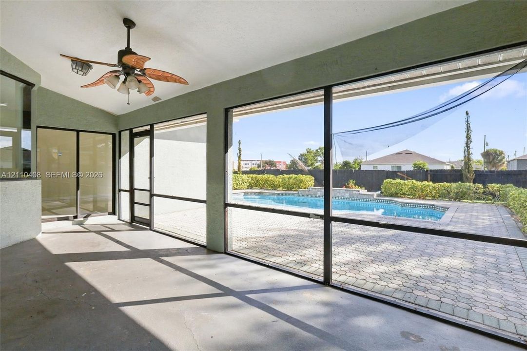 Screened lanai featuring a ceiling-mounted paddle fan and concrete flooring, exterior space with a paver patio and swimming pool