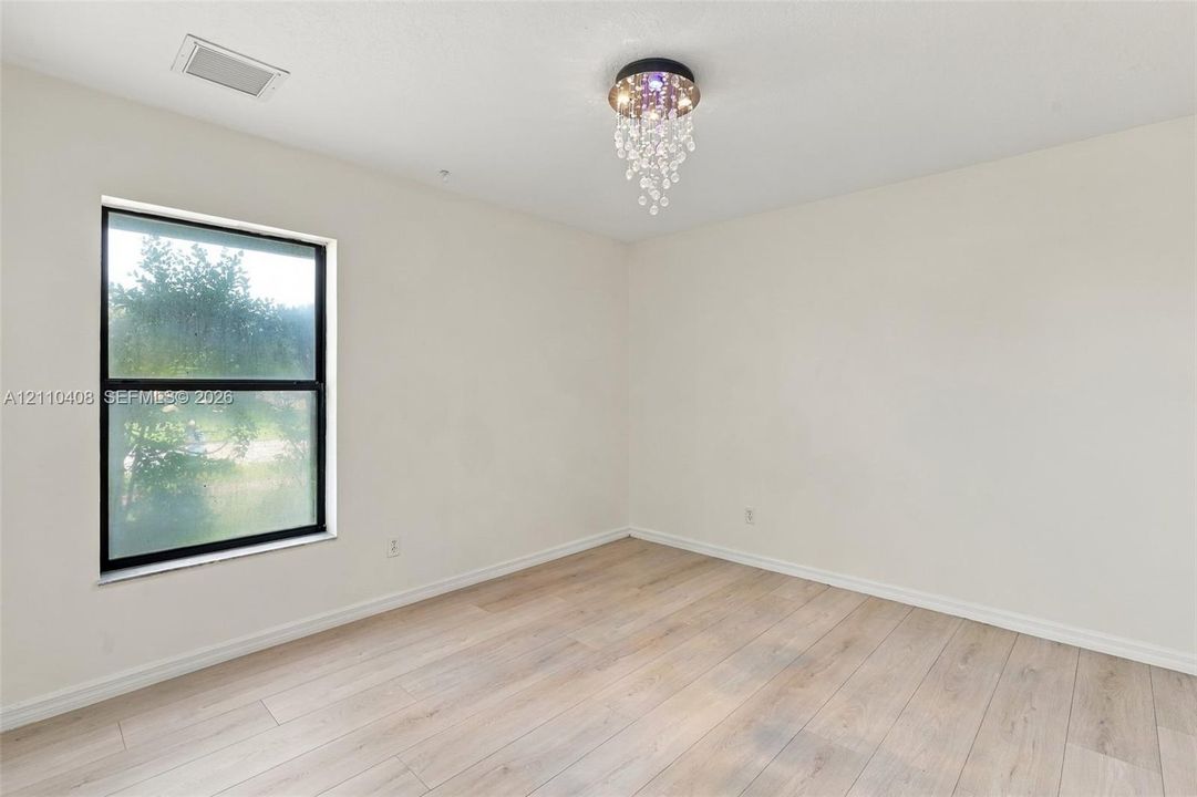 Neutral walls, wood-finish flooring, and a crystal-accented flush-mount light fixture