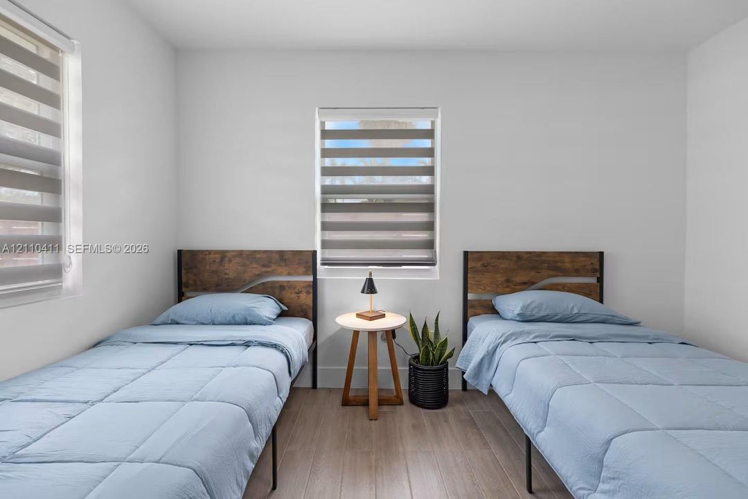 Neutral-toned walls, wood-finish flooring, and dual windows equipped with horizontal-striped roller shades