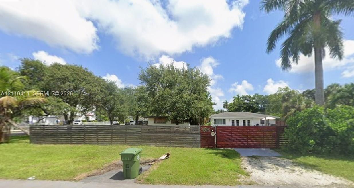 Single-story residence featuring a horizontal wood-slat privacy fence, gated entry, and mature perimeter landscaping