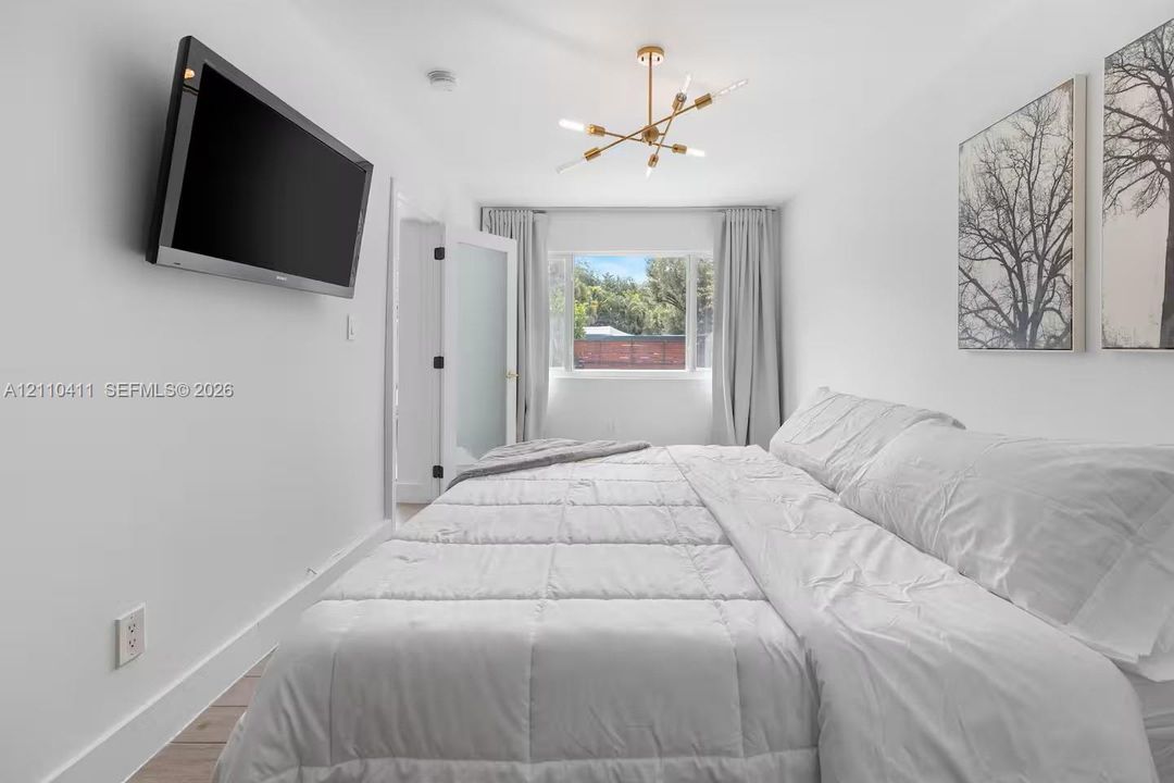 Sputnik-style gold-tone chandelier, wall-mounted television, and frosted glass pane door