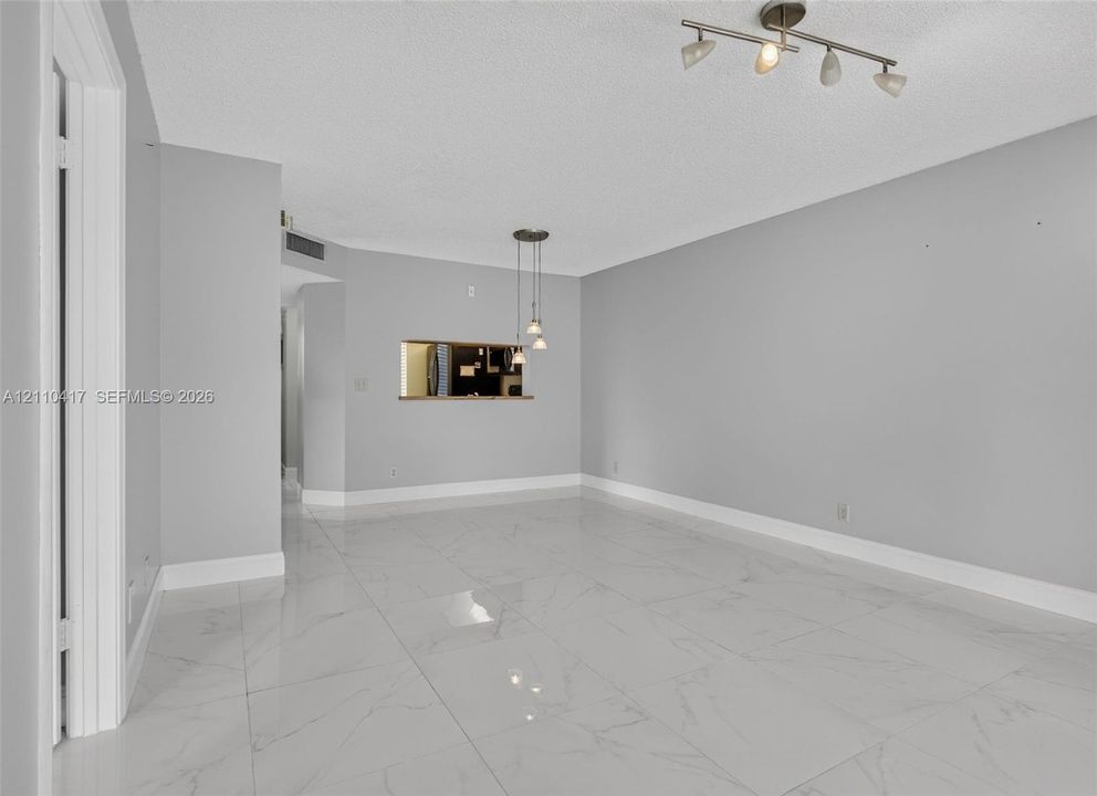 Large-format tile flooring, recessed pass-through window, three-light pendant fixture, and multi-directional track lighting