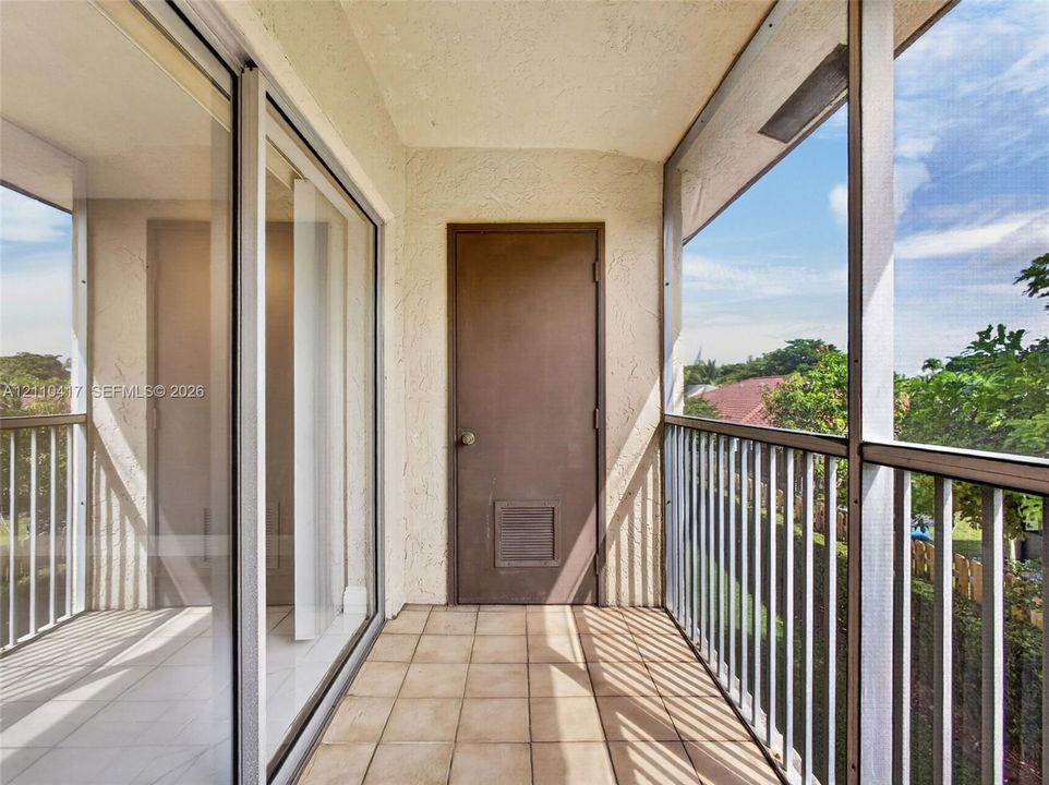 Covered balcony featuring ceramic tile flooring, a screen enclosure, metal railings, and sliding glass entry doors