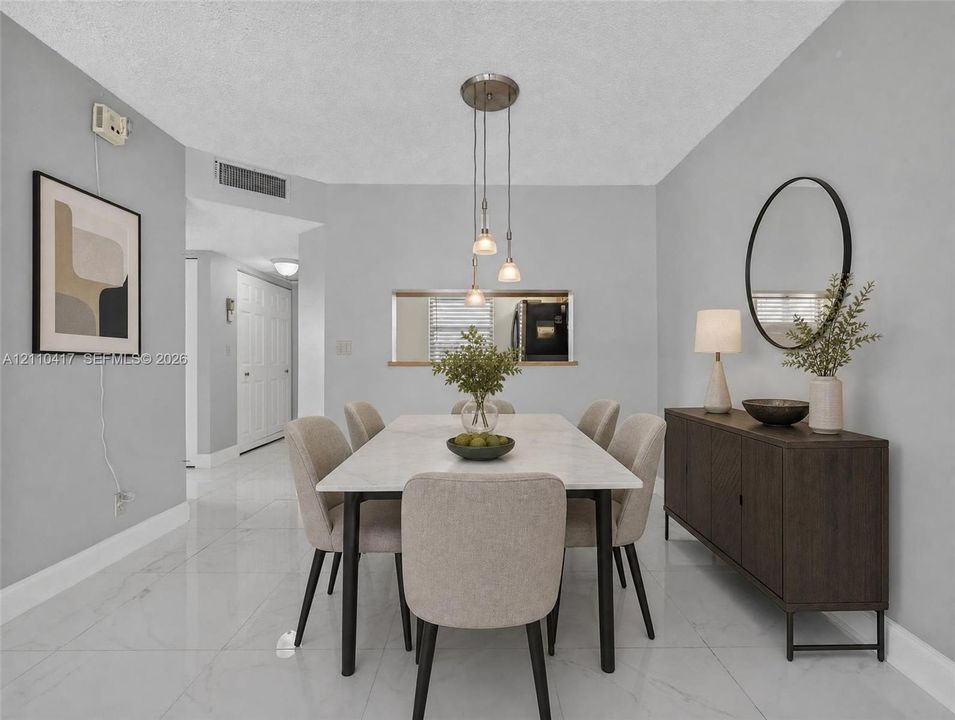 Dining area featuring neutral wall paint, polished tile flooring, a multi-pendant light fixture, and an interior pass-through window