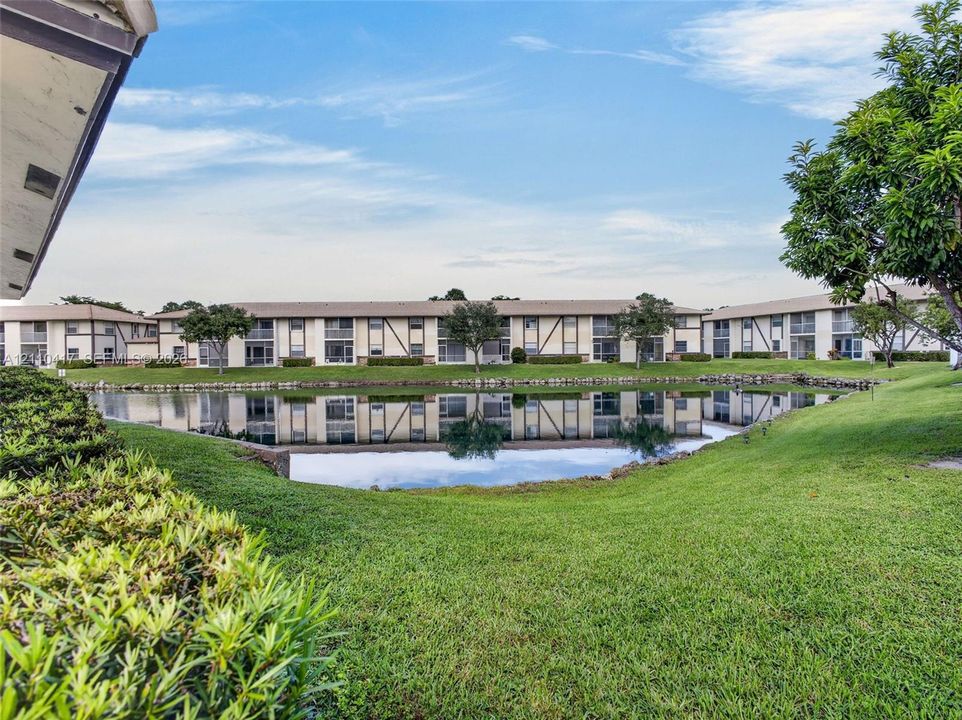 Multi-level exterior with stucco facade featuring a central water feature, stone-lined pond edges, and landscaped green space