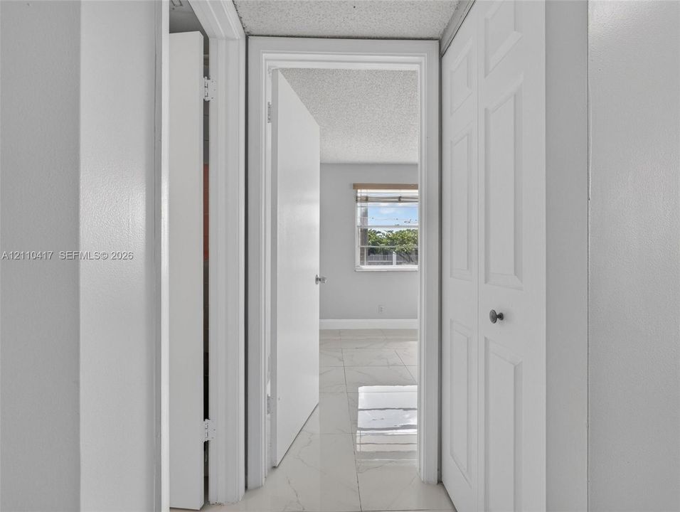 Light-colored tile flooring, white interior doors, and a double-panel closet door