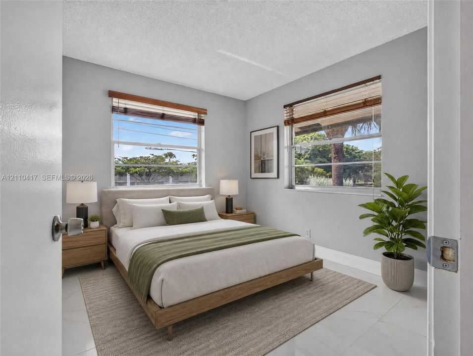 Bedroom featuring light-toned neutral walls, polished tile flooring, and dual windows with wooden blinds