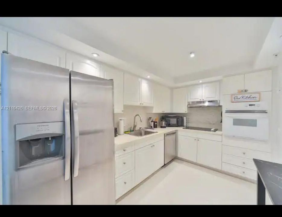 Kitchen featuring white cabinetry, solid-surface countertops, stainless steel appliances, a double-door refrigerator, and recessed lighting