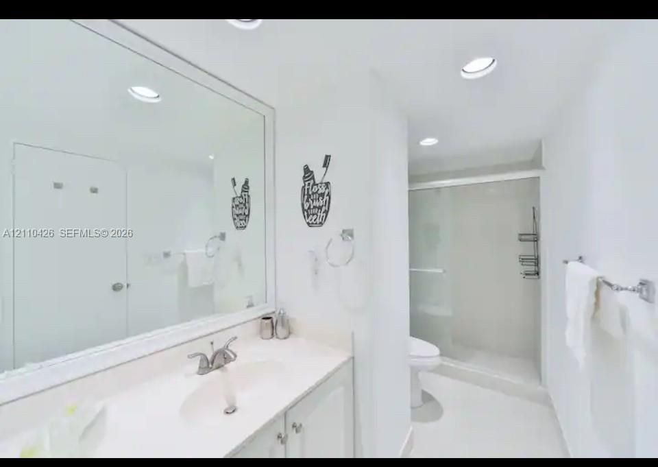 Full-width mirror, vanity with integrated sink, chrome-finished hardware, and walk-in shower enclosure with sliding glass doors