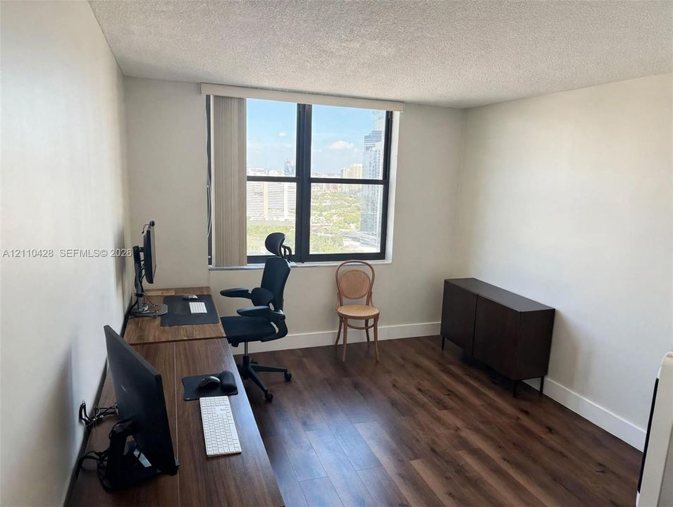 Multi-pane window with vertical blinds, wood-finish flooring, and painted interior walls