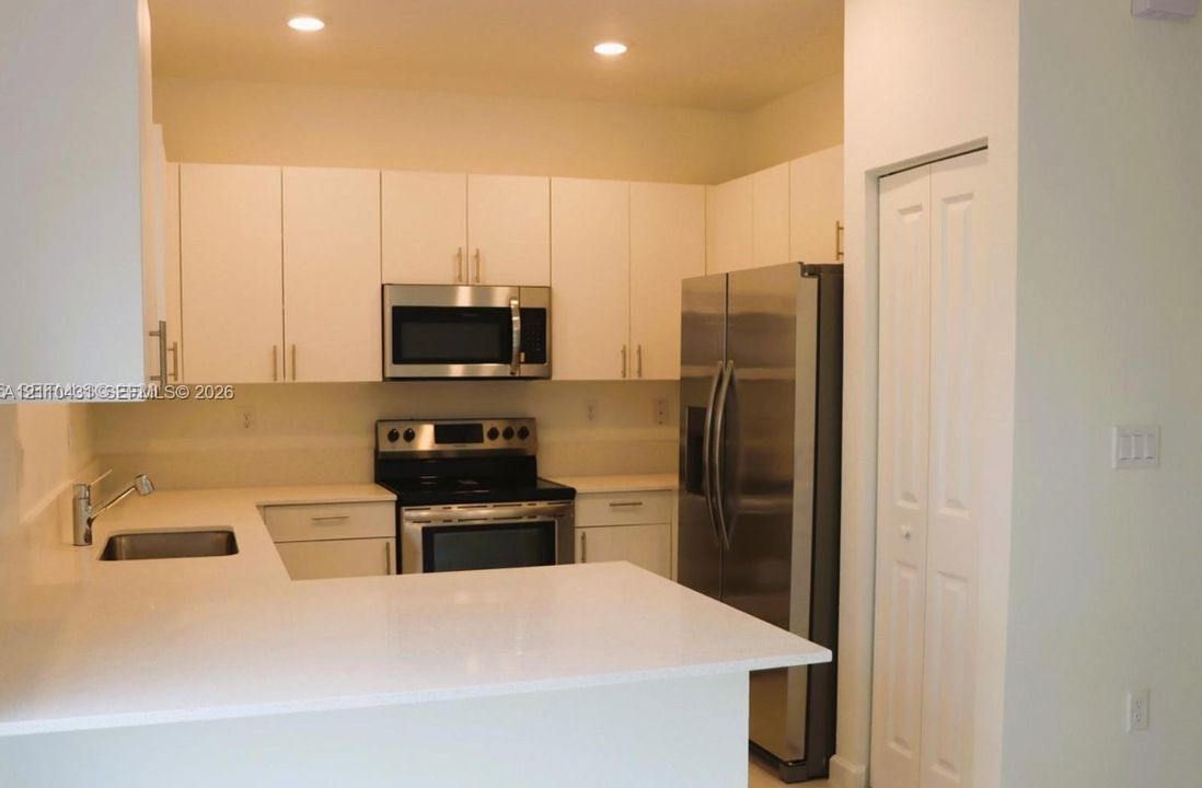 Kitchen featuring white cabinetry, solid-surface countertops, recessed lighting, and stainless steel appliances