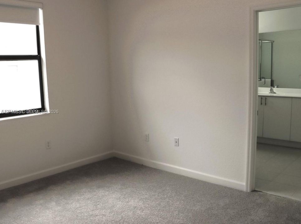 Neutral-toned interior room with wall-to-wall carpeting and a single-pane window