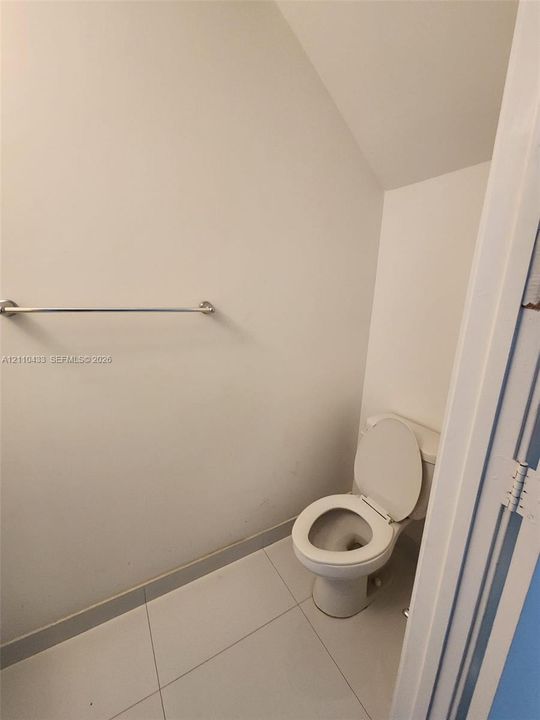 Restroom featuring large-format ceramic floor tile, a standard porcelain toilet, and a wall-mounted metal towel bar