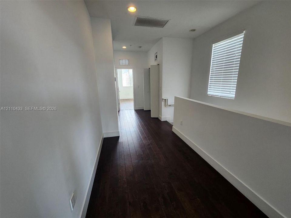 Dark wood-finish flooring, recessed lighting, and a window with horizontal blinds