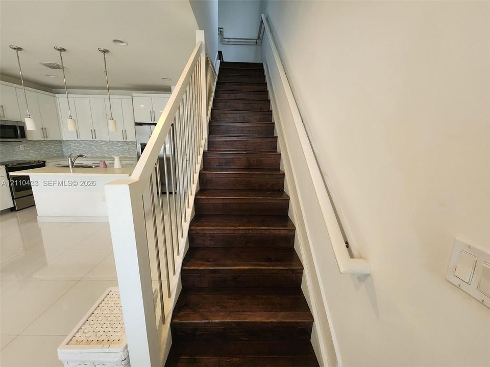 Staircase featuring dark wood-finish treads, white balusters, and a mounted handrail