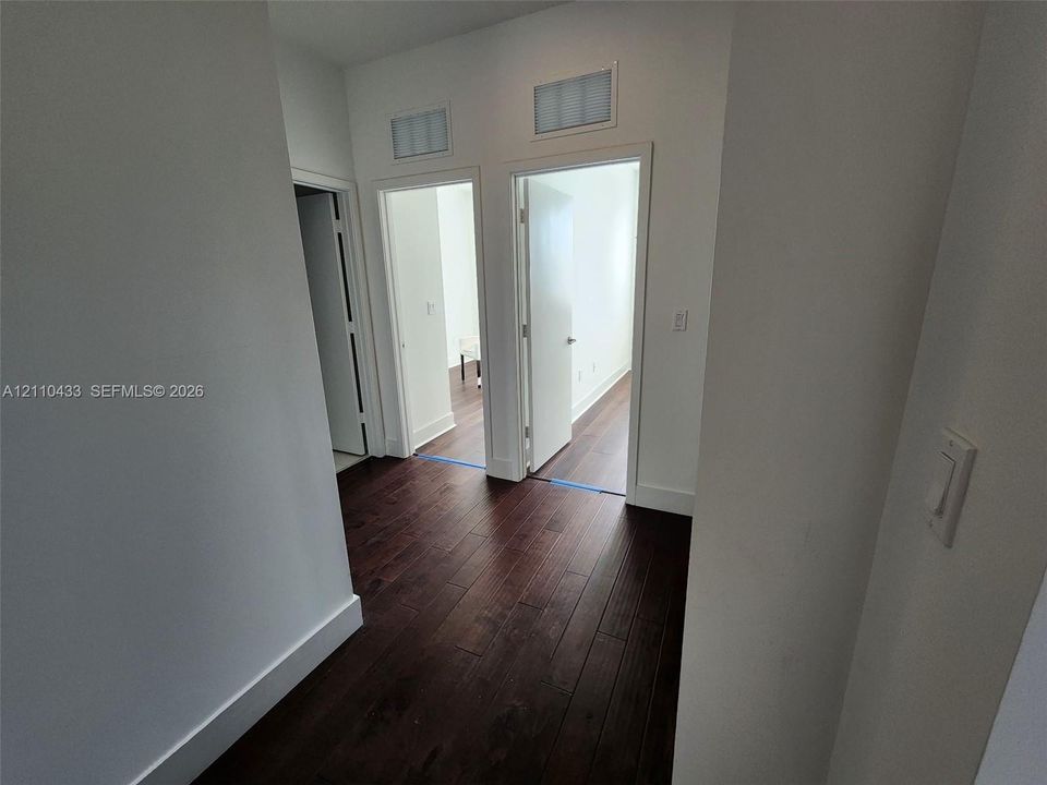 Dark wood-finish flooring, crisp white walls, and interior passage doors with satin nickel hardware