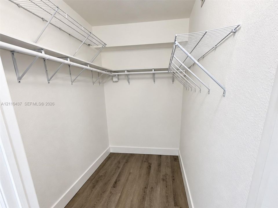 Walk-in closet featuring wood-finish flooring and integrated white wire shelving