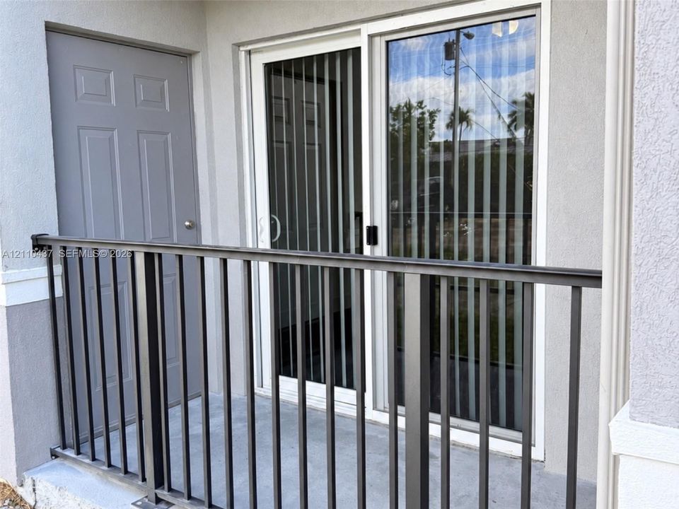 Private balcony featuring a concrete floor, dark metal railing, and a full-height utility closet door