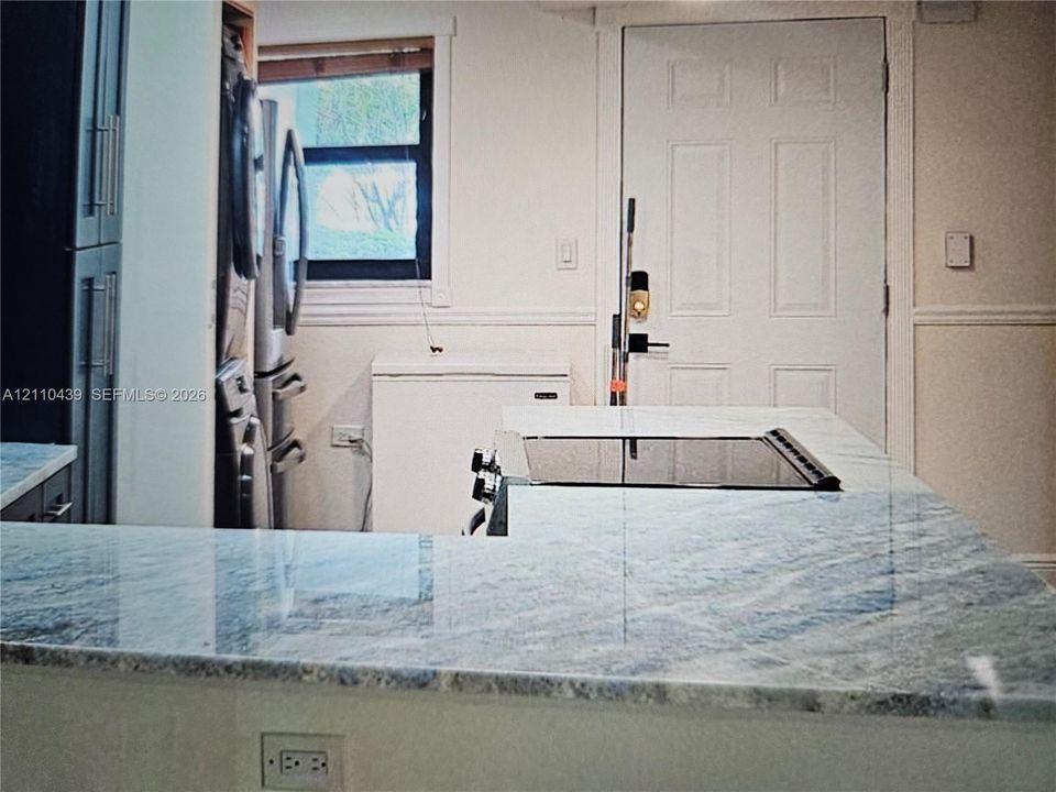 Kitchen featuring a stone-surface island, integrated cooktop, and dark cabinetry
