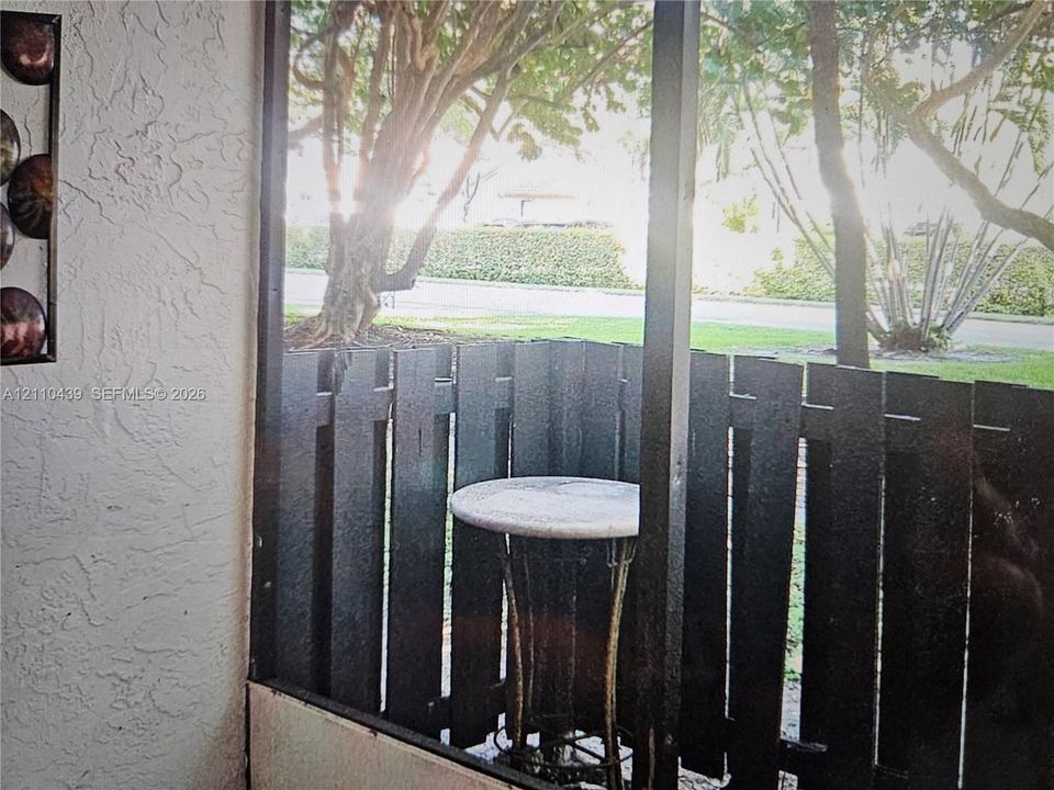 Screened-in outdoor area featuring textured stucco walls and vertical wood slat privacy fencing
