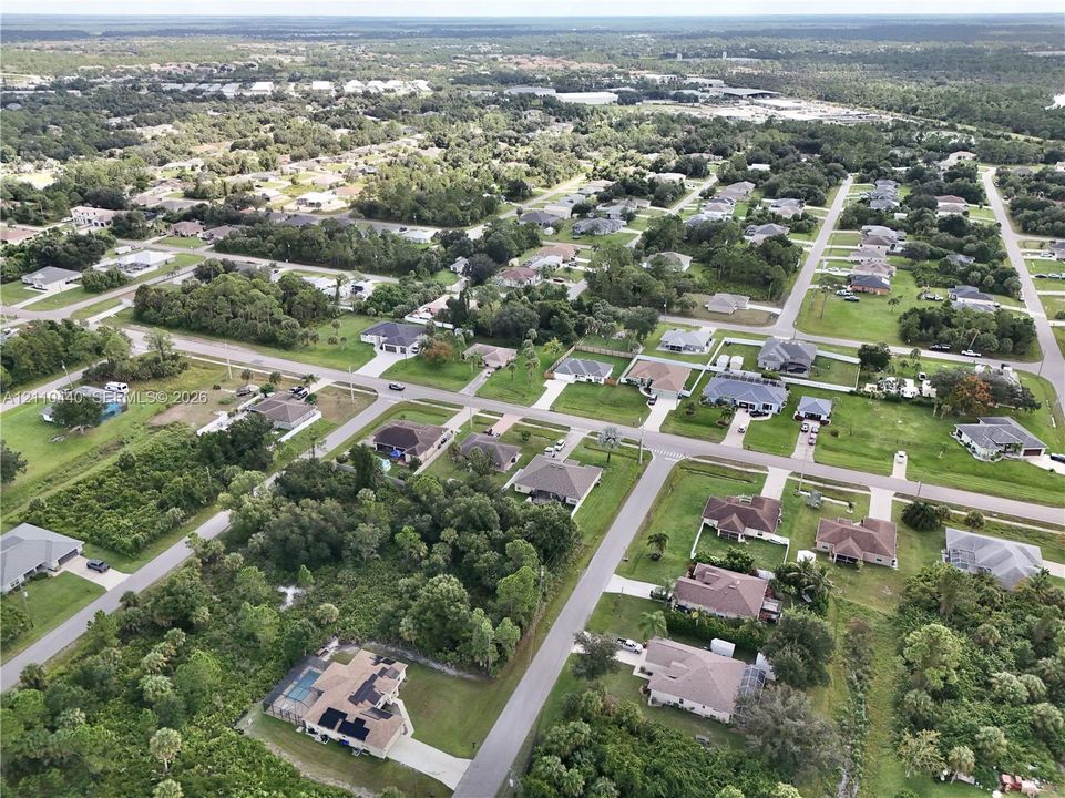 Aerial perspective of a residential neighborhood featuring paved streets, established landscaping, mature trees, and varying lot sizes
