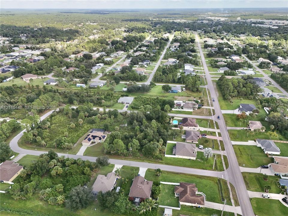 Aerial perspective of a suburban neighborhood featuring paved streets, mature trees, and residential structures with shingle-style roofs