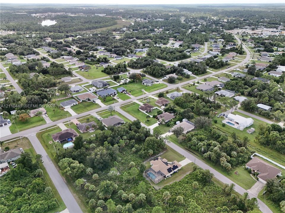 Aerial perspective of a residential neighborhood featuring paved roadways, platted lots, mature vegetation, and residential structures with shingle roofing