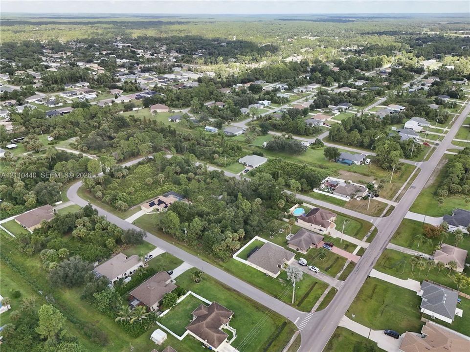 Aerial perspective of a residential neighborhood featuring paved roadways, detached single-story residences, and abundant native vegetation