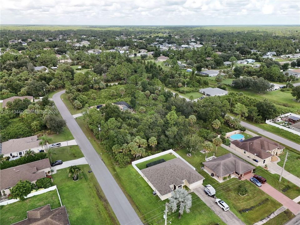 Aerial perspective featuring a single-story residence with a multi-gabled roofline, expansive corner lot, and established native landscaping