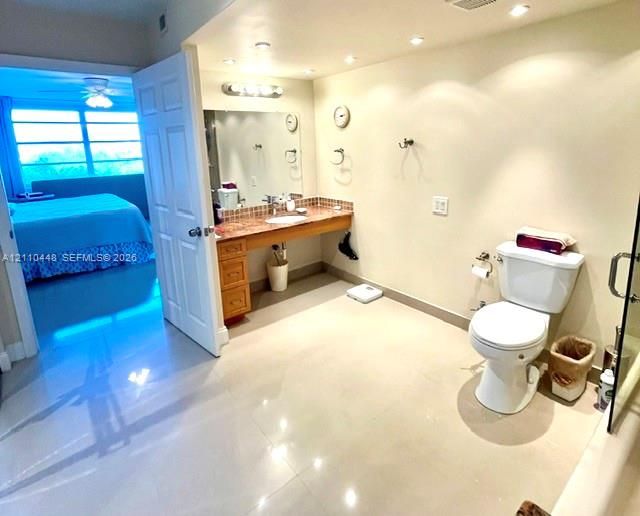 Bathroom featuring a natural stone-topped vanity with built-in cabinetry, polished tile flooring, recessed ceiling lighting, and a wall-to-wall mirror