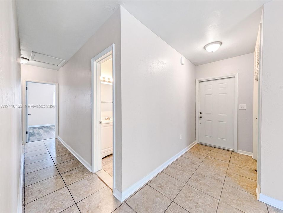 Entryway featuring ceramic tile flooring, a six-panel exterior door, and flush-mount ceiling lighting