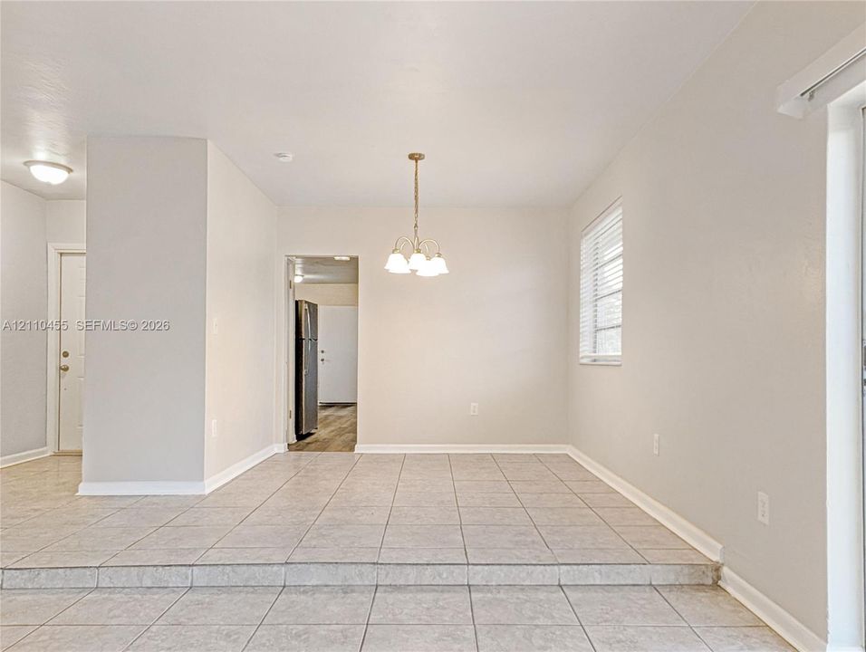 Dining space featuring a raised tile floor, neutral wall paint, a three-light chandelier, and window blinds