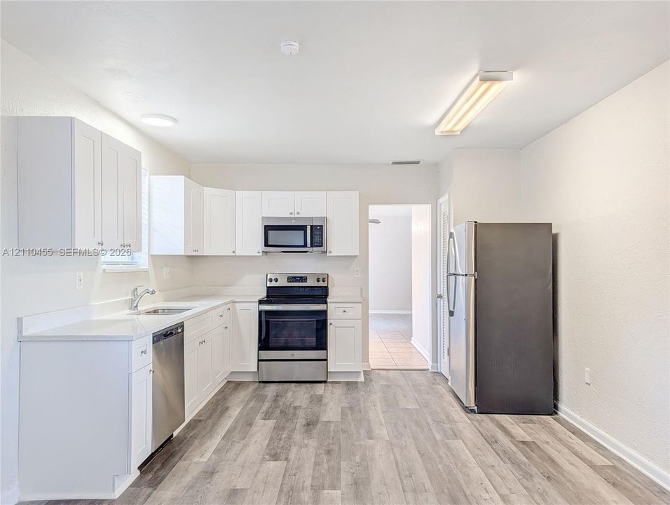 Kitchen featuring white cabinetry, wood-finish flooring, stainless steel appliances, and integrated microwave