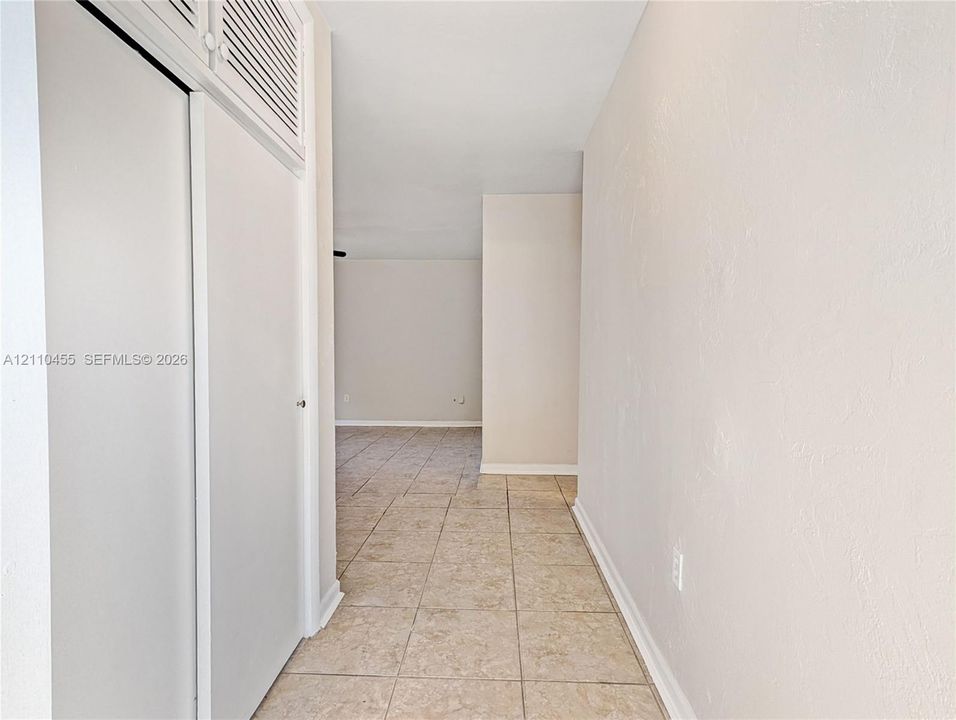 Ceramic tile flooring throughout with built-in closet featuring louvered upper storage cabinet