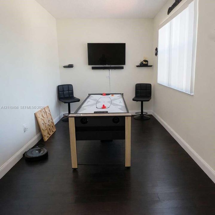 Room featuring dark-toned wood-finish flooring, neutral wall coloring, and vertical blinds