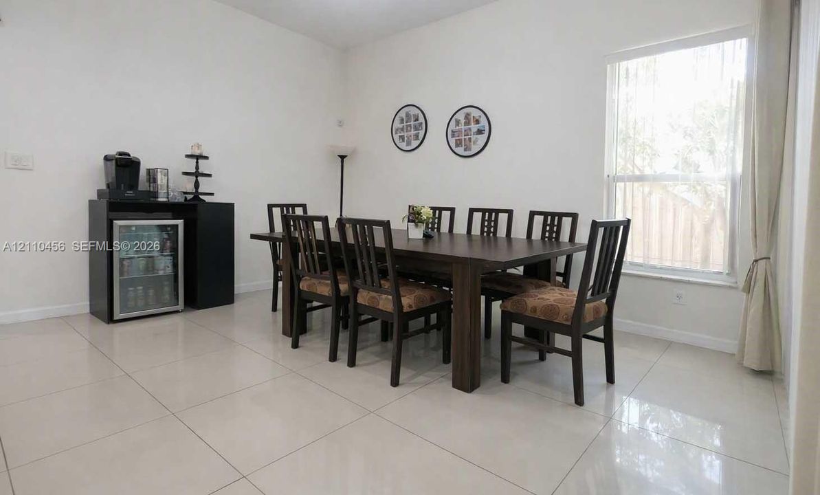 Spacious room featuring neutral large-format tile flooring and a large window with vertical blinds