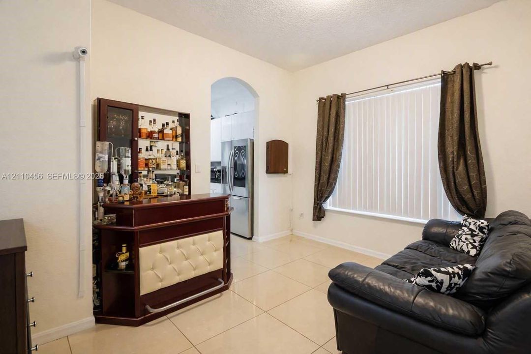 Large-format tile flooring, arched doorway, and neutral wall tones