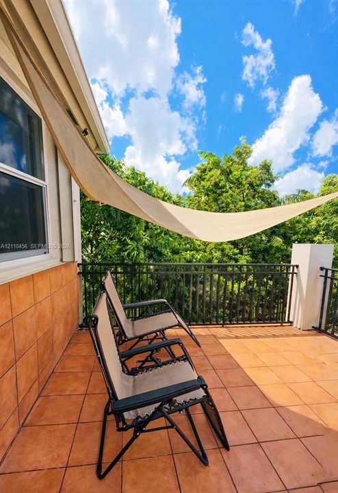 Private balcony featuring tile flooring, metal railing, and wall-mounted tile exterior finish
