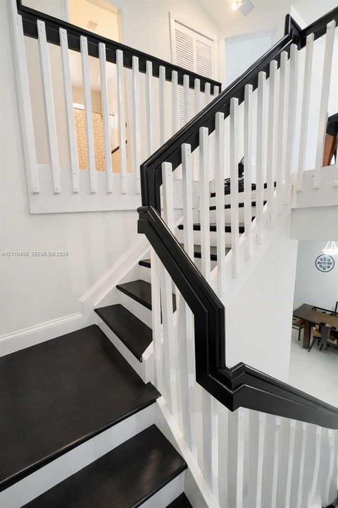 Staircase featuring dark-stained wood treads, contrasting white risers, and a custom railing system with a dark-stained handrail and white balusters