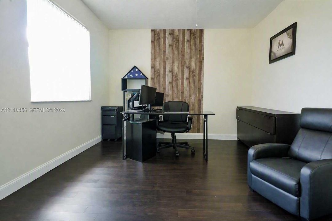Dark-toned wood-finish flooring complemented by a vertical wood-plank accent wall and a large window